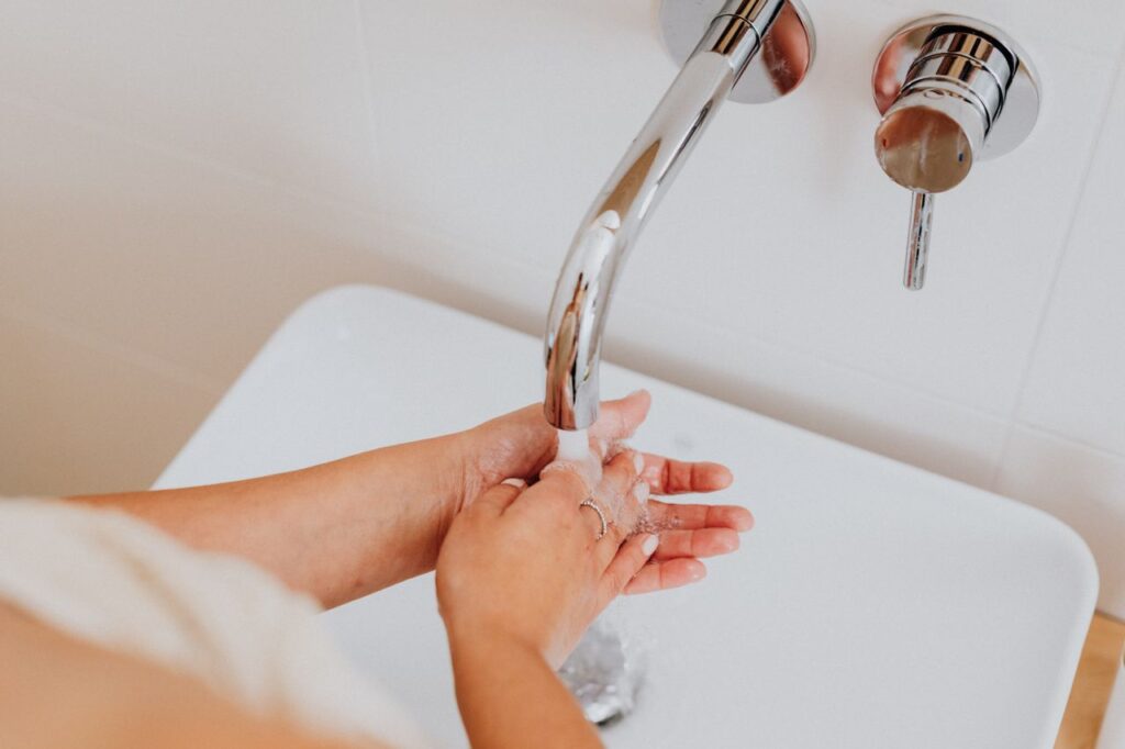 A close-up of hands washing under a modern faucet, promoting hygiene.